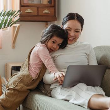 Mother and daughter hugging and watching laptop
