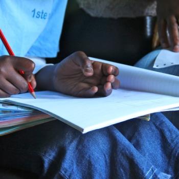 boy writing while sitting on a sofa