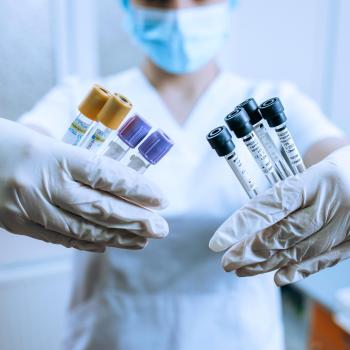 medical technician with gloved hands holding testtubes