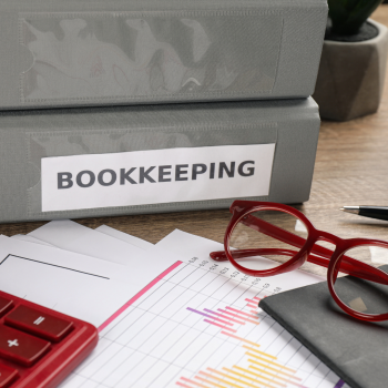 A calculator, glasses and binders labelled "BOOKKEEPING"
